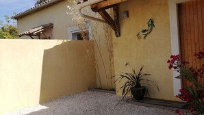 A building with a yellow exterior, a wooden door, and a small potted plant in front. - Gîte 1 bed, sleeps 3, garden and parking, small swimming pool, 15 mins from the sea. (La Crau)