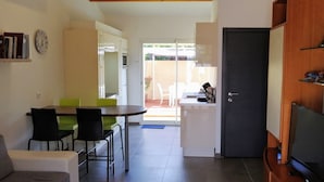 A compact living space with a dining area, a kitchen, and a TV. - Gîte 1 bed, sleeps 3, garden and parking, small swimming pool, 15 mins from the sea. (La Crau)