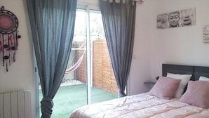 A bedroom with a bed, curtains, a dreamcatcher, and a view of a garden. - Gîte 1 bed, sleeps 3, garden and parking, small swimming pool, 15 mins from the sea. (La Crau)