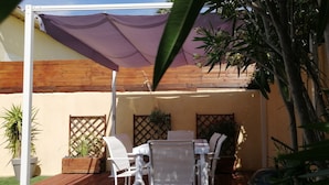 A patio with a table and chairs, surrounded by wooden fences and potted plants. - Gîte 1 bed, sleeps 3, garden and parking, small swimming pool, 15 mins from the sea. (La Crau)