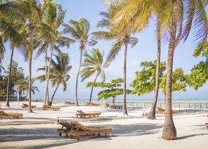 A beach with palm trees, wooden lounge chairs, and a sandy area. - VRclub - Paje Palms Beach Resort (Paje)