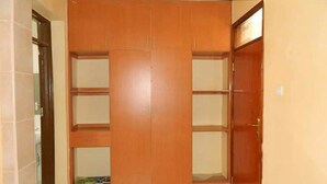 Una habitación con armario de madera, suelo de baldosas y una alfombra pequeña.