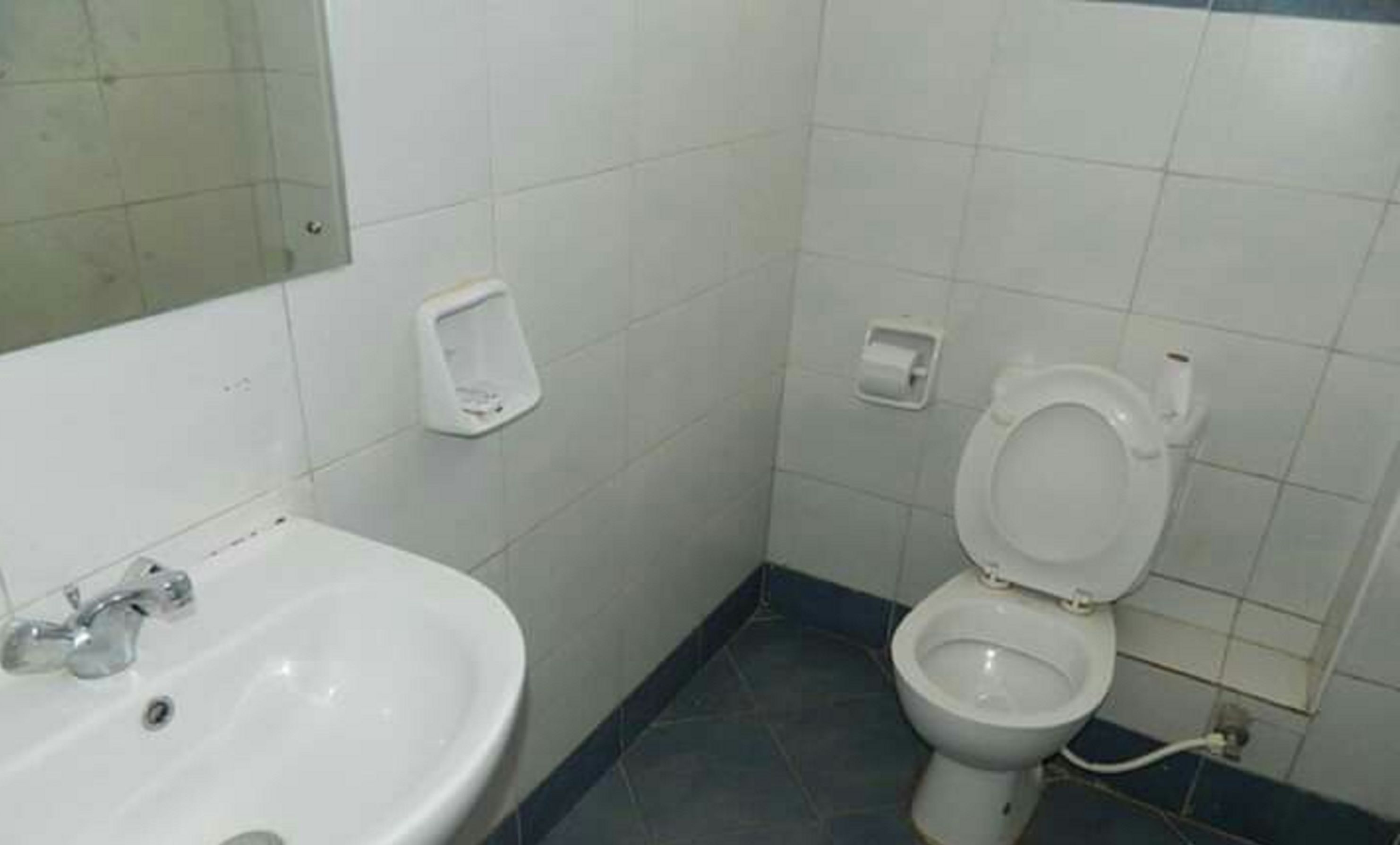 Une salle de bain avec un lavabo blanc, des toilettes et un miroir.