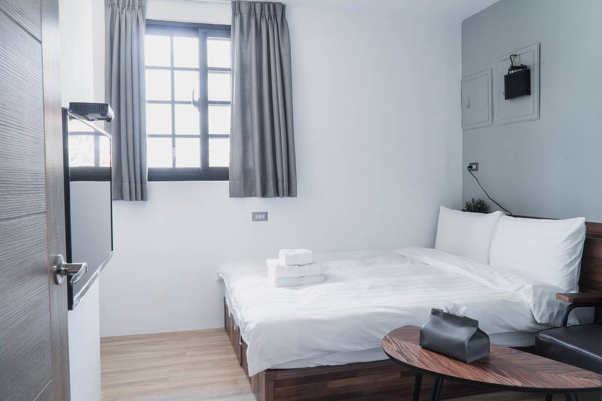 A neatly arranged bedroom with a bed, bedside table, and a small round table.