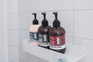 Three bottles of Cha Izu Tang body wash on a white shelf in a bathroom. - Beizhu Tainan Homestay (Tainan)