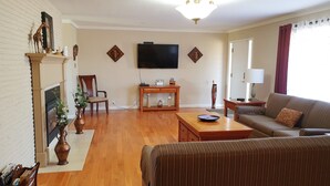 A living room with a fireplace, a television mounted on the wall, a sofa, a coffee table, and a side table with a lamp. - West Yakima - Clean - Safe - Netflix - 4212 - ONWU-LLC (Yakima)