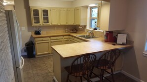 A compact kitchen with a central island, two wooden chairs, and a window providing natural light. - West Yakima - Clean - Safe - Netflix - 4212 - ONWU-LLC (Yakima)