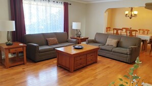 A living room with two sofas, a coffee table, a lamp, and a dining area with chairs and a table. - West Yakima - Clean - Safe - Netflix - 4212 - ONWU-LLC (Yakima)