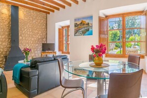 Un salon avec une table en verre, un canapé en cuir et un mur en pierre.