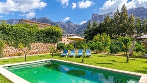 A swimming pool with lounge chairs, surrounded by greenery and mountains in the background. - Captivating Mallorcan Villa With A Pool In Soller (Sóller)