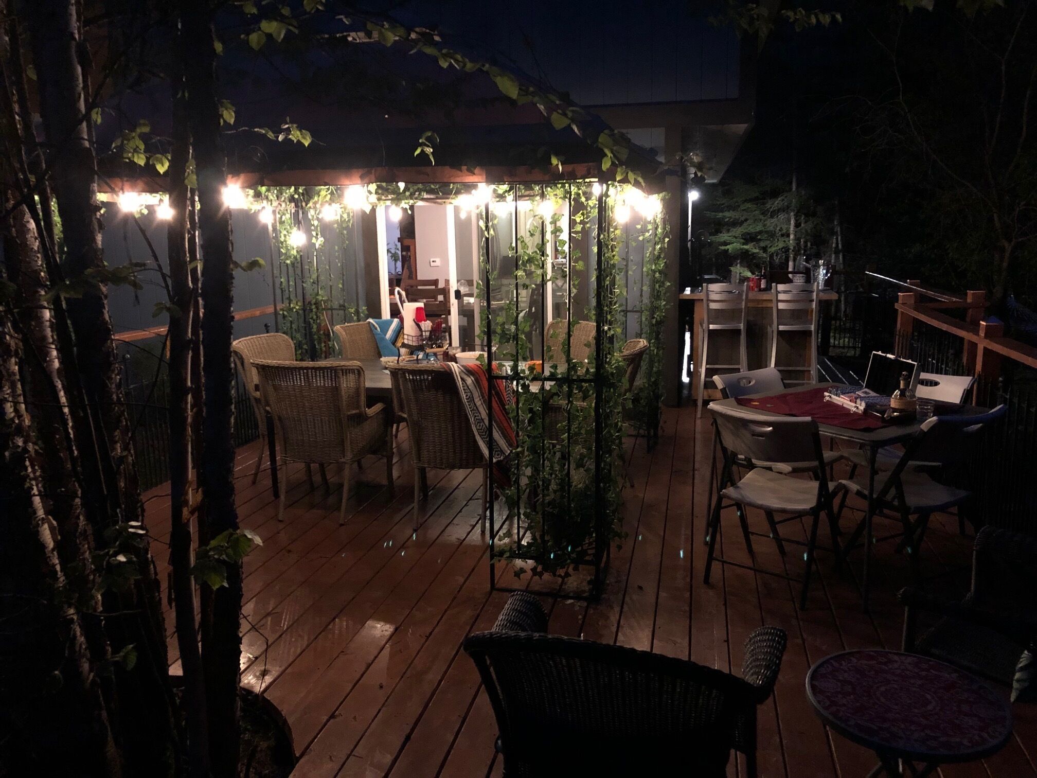 An outdoor patio with wicker furniture, string lights, and a wooden deck.