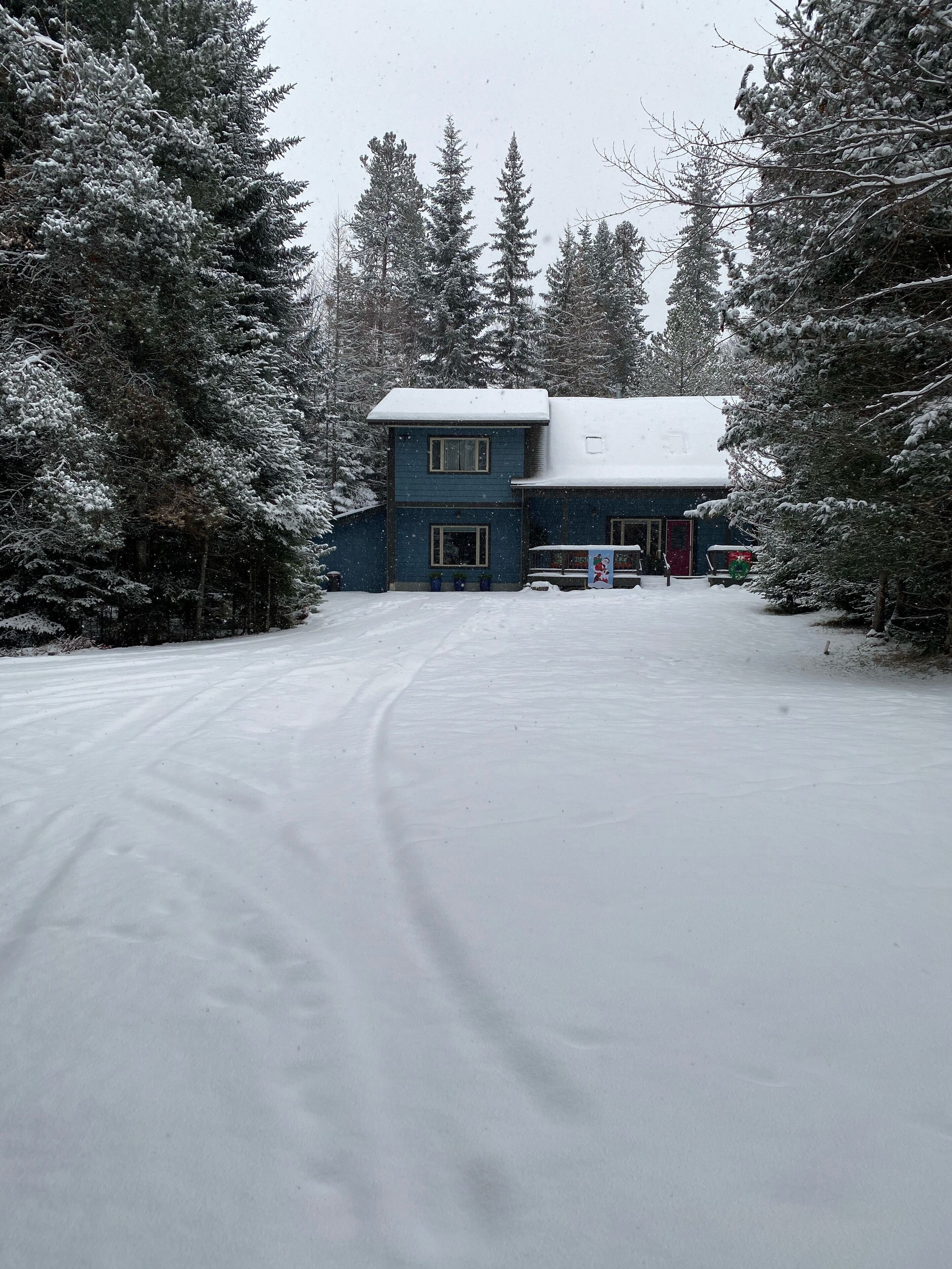 A two-story building with a snow-covered roof, surrounded by snow-laden trees.