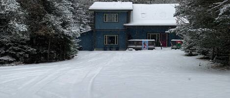 A two-story building with a snow-covered roof, surrounded by snow-laden trees.