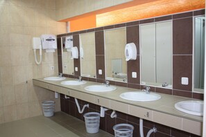 A public restroom with three sinks, mirrors, and hand dryers.