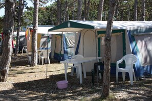 A campsite with tents, plastic chairs, and a picnic table.