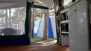 A tented camping area with a wooden deck, a white refrigerator, and a view of trees. - Kamp Planik- Campsite (Razanac)