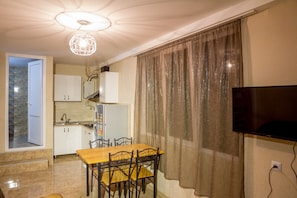 Cozy living space with a kitchenette, dining area, and flat-screen TV.