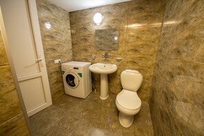 Bathroom features a pedestal sink, toilet, and washing machine.