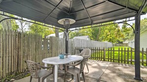 An outdoor patio with a round table and chairs, a metal lamp, and a wooden fence.