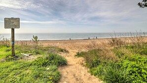 A beach path leading to the ocean with a signboard.