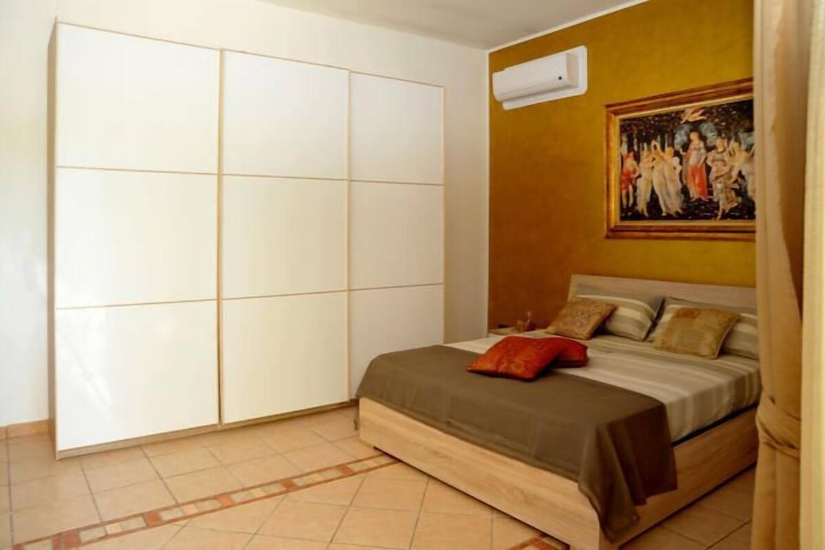 Un dormitorio con cama, armario y un cuadro en la pared.