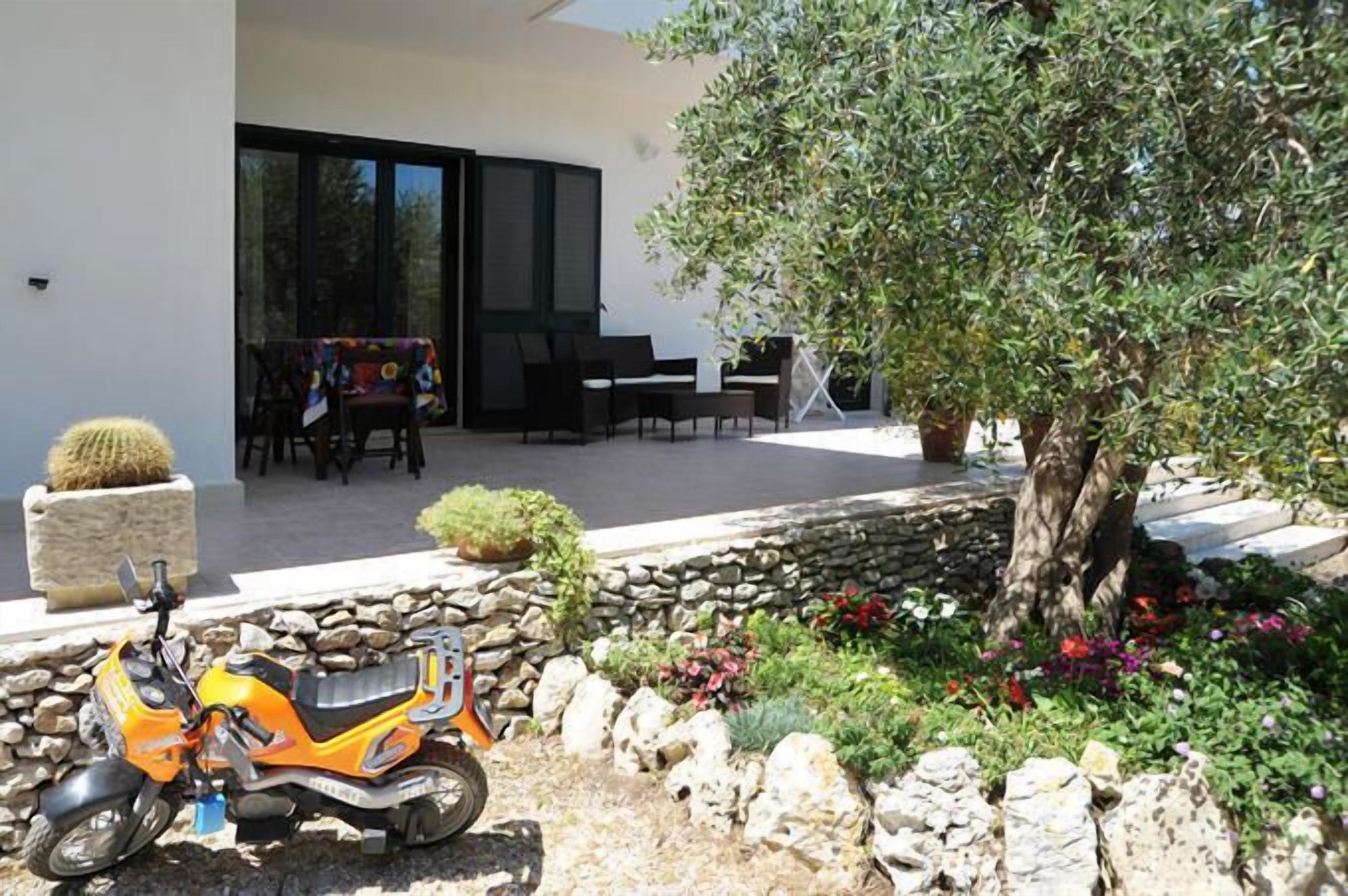 A patio with outdoor furniture, a tree, and a scooter.