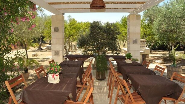 A covered outdoor dining area with multiple tables and chairs, surrounded by greenery and trees. - Vacanze al Minci (Giurdignano)