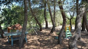 A forested area with a picnic table and a children's play structure. - Vacanze al Minci (Giurdignano)