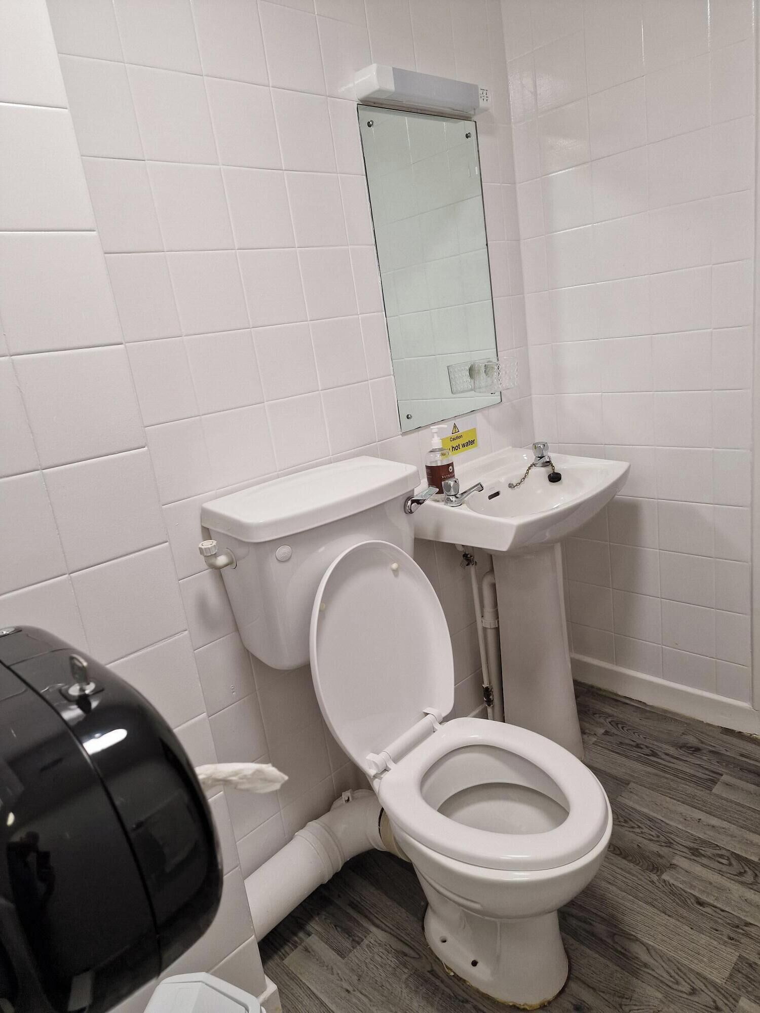 A bathroom with a toilet, sink, and mirror.