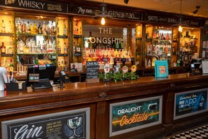 A bar with a wooden counter, various liquor bottles, and a sign for draught cocktails. - The Longship By Greene King Inns (Hebburn)