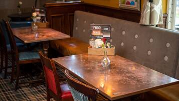 A restaurant interior with wooden tables and benches, a menu stand, and a patterned floor.