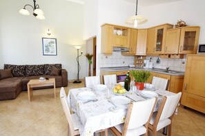 A compact living space with a dining area, a kitchen with wooden cabinets, and a living room with a sofa and a coffee table.