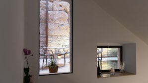 Una habitación con pared de piedra, una planta en maceta y ventana con vista a un área de estar al aire libre.