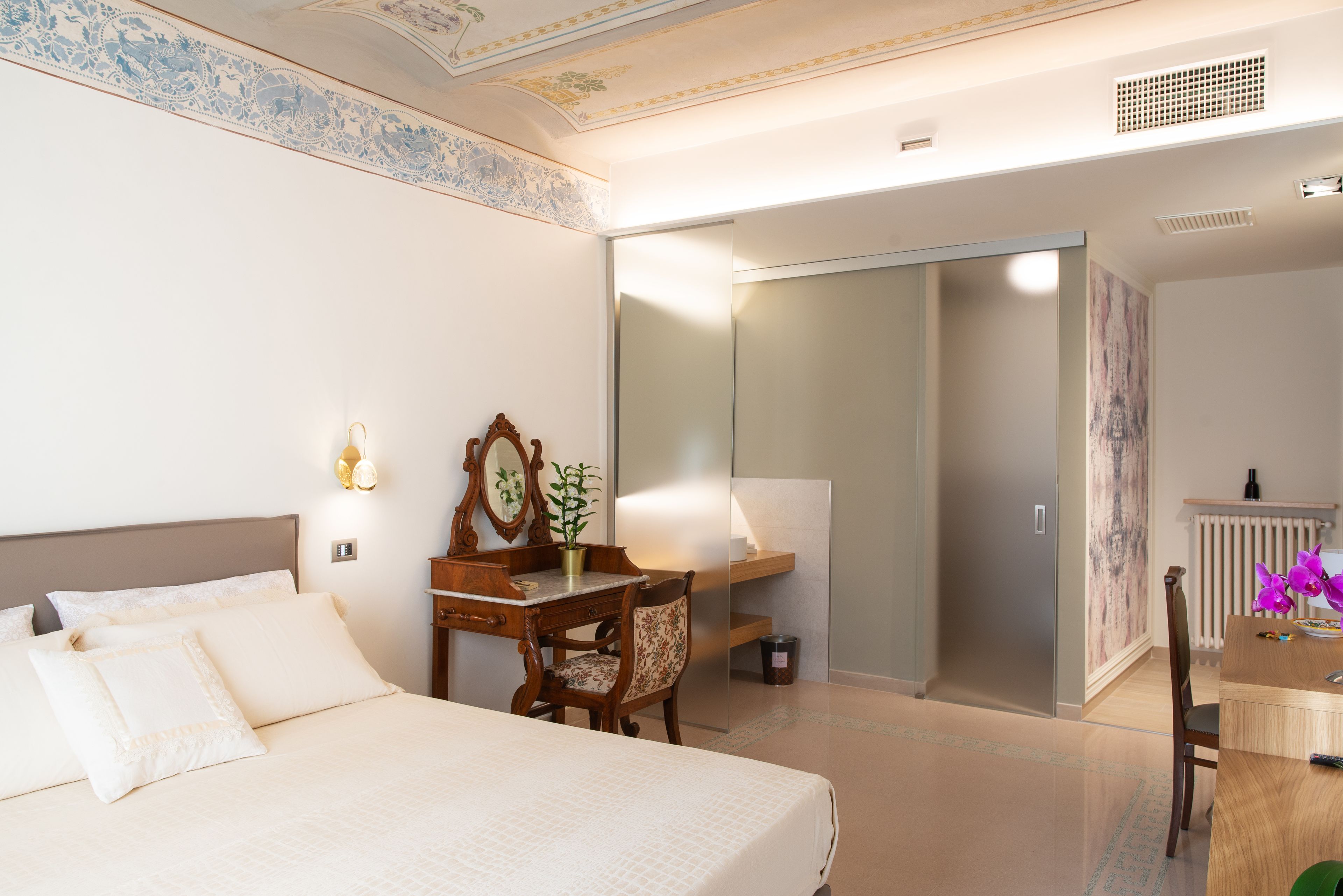 Een hotelkamer met een bed, een bureau, een stoel, een spiegel en een kledingkast.