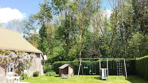 A backyard with a brick house, a swing set, and a small shed.