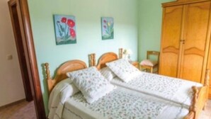 Ein Schlafzimmer mit zwei Einzelbetten, einem Holzschrank und zwei Blumenbildern an der Wand.