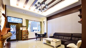 A modern living room with a sofa, a coffee table, and a dining area with chairs and a table. - Kai Feng B&B (Taitung)