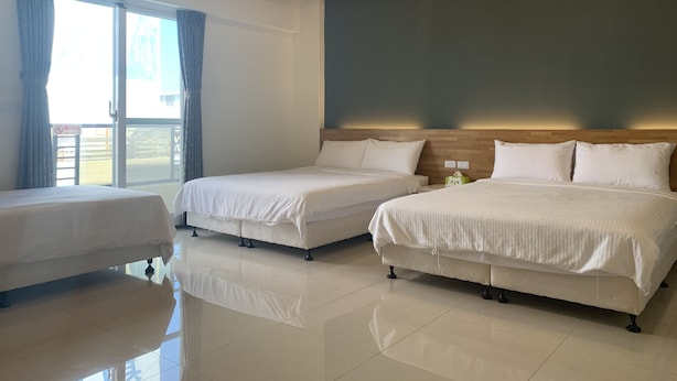 A hotel room with two beds, a large window, and a wooden ceiling. - Kai Feng B&B (Taitung)