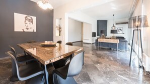 Un comedor moderno con una mesa de mármol, sillas negras y una lámpara de araña.