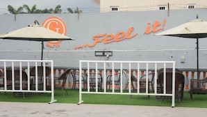 A wall with the text "Feel it!" and a logo. There are outdoor chairs and umbrellas in front of a white fence. - Galpin Suites Ikeja (Lagos)