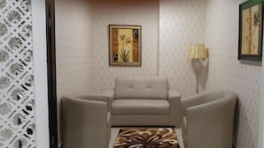 A room with a sofa, a lamp, and two framed pictures on the wall. - Galpin Suites Ikeja (Lagos)