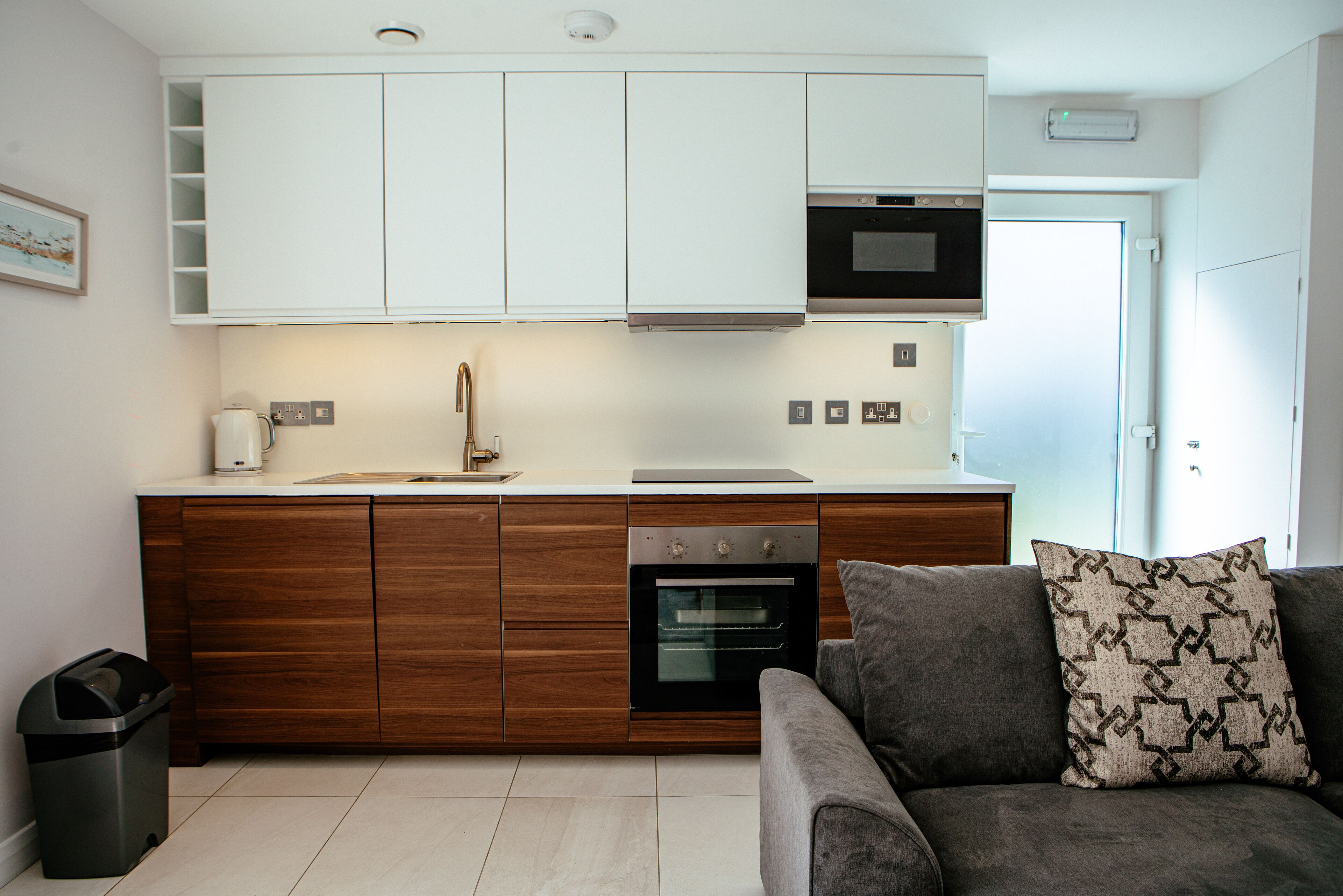 A compact kitchen with white cabinets, a built-in oven, and a microwave.