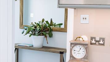 Una cocina con microondas, un reloj y una planta en maceta sobre una estantería.