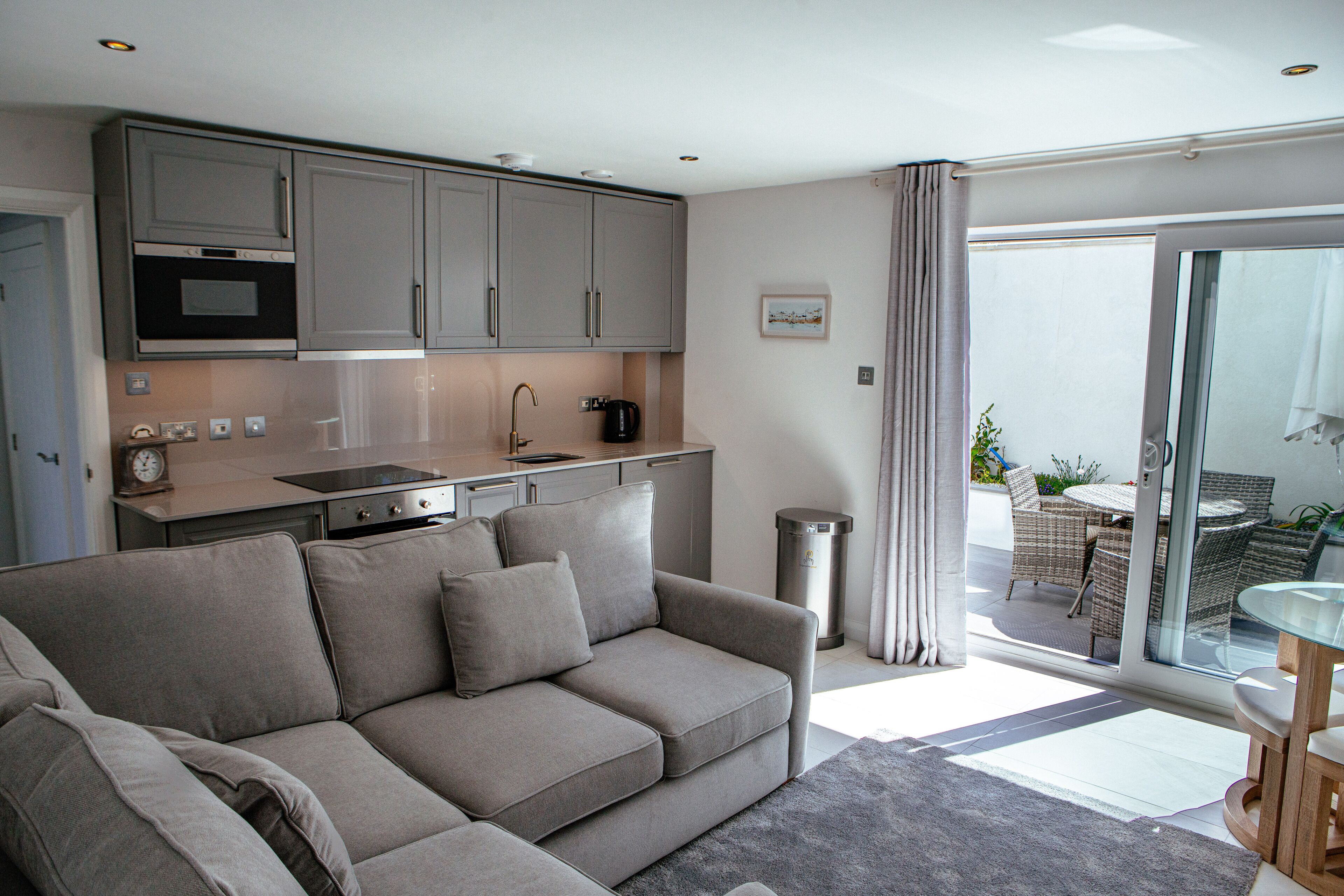 A modern kitchen with grey cabinets, a built-in oven, and a coffee maker.