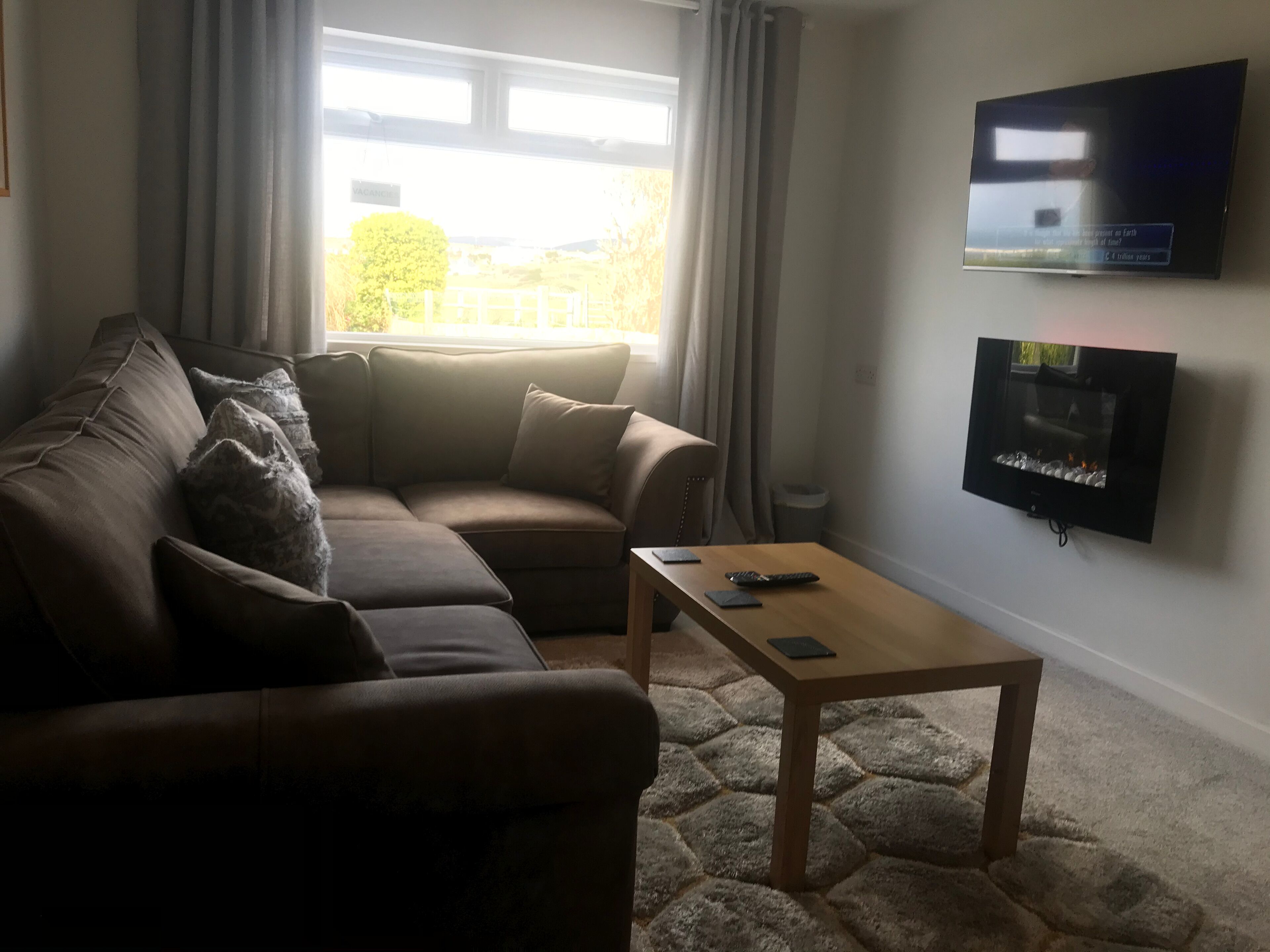 A living room with a sofa, a coffee table, and a flat-screen TV mounted on the wall.