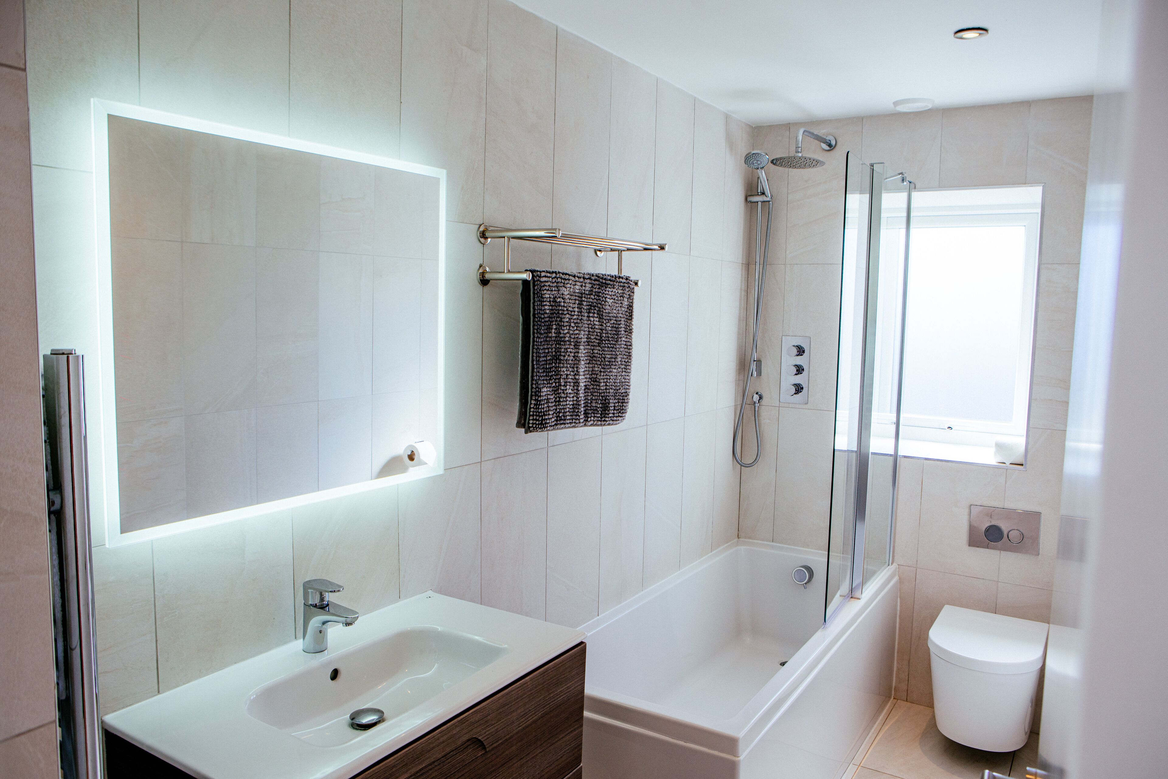 A modern bathroom with a large mirror, a sink, a bathtub, and a shower.
