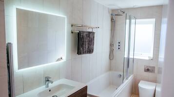 A modern bathroom with a large mirror, a sink, a bathtub, and a shower.