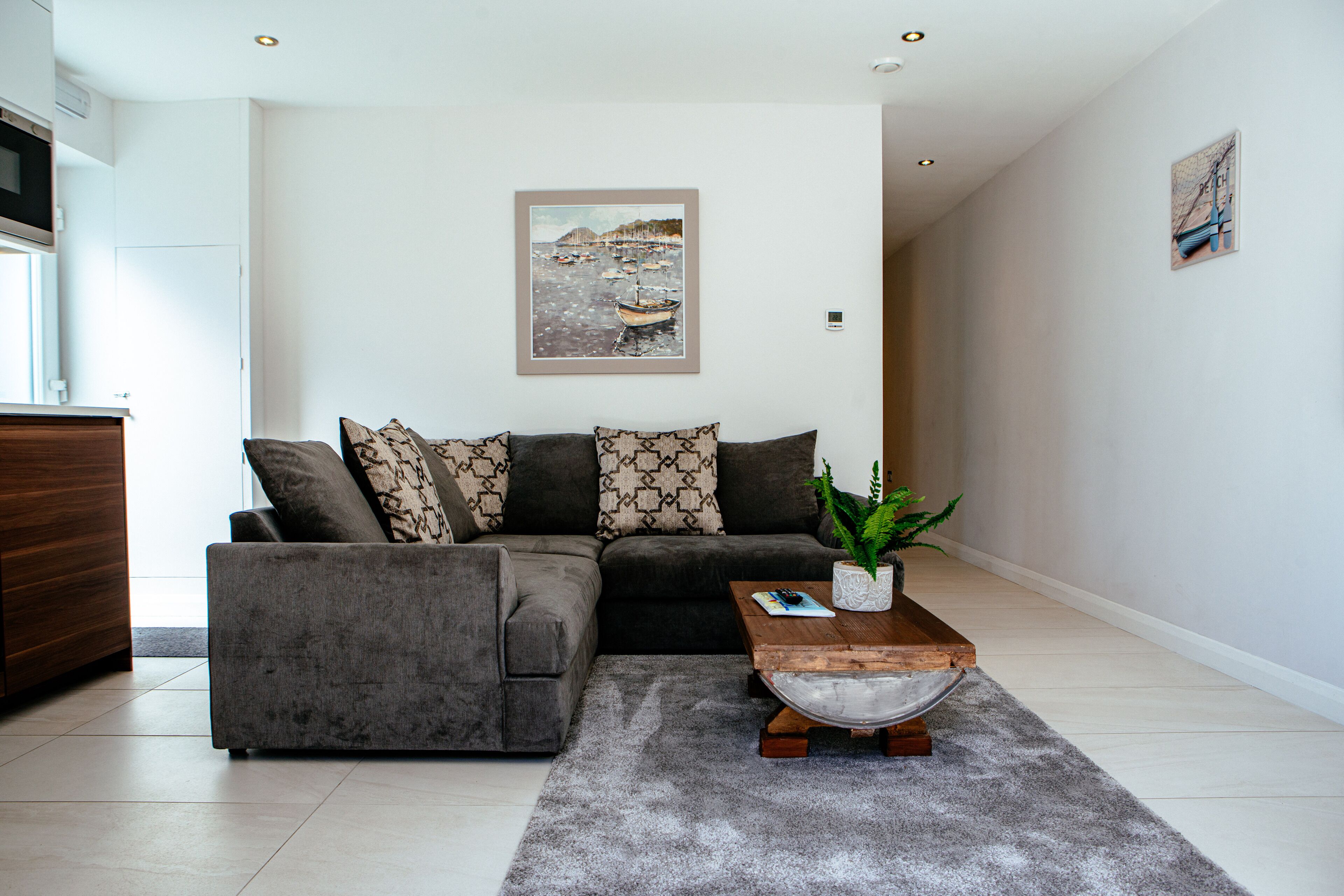 A modern living room with a grey sectional sofa, a wooden coffee table, and a grey rug.