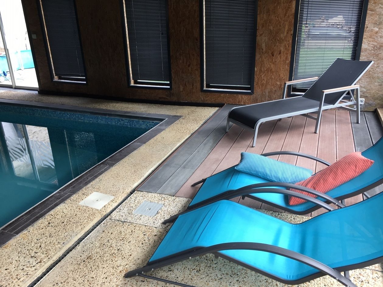 Zona junto a la piscina con sillones de descanso y una piscina pequeña.