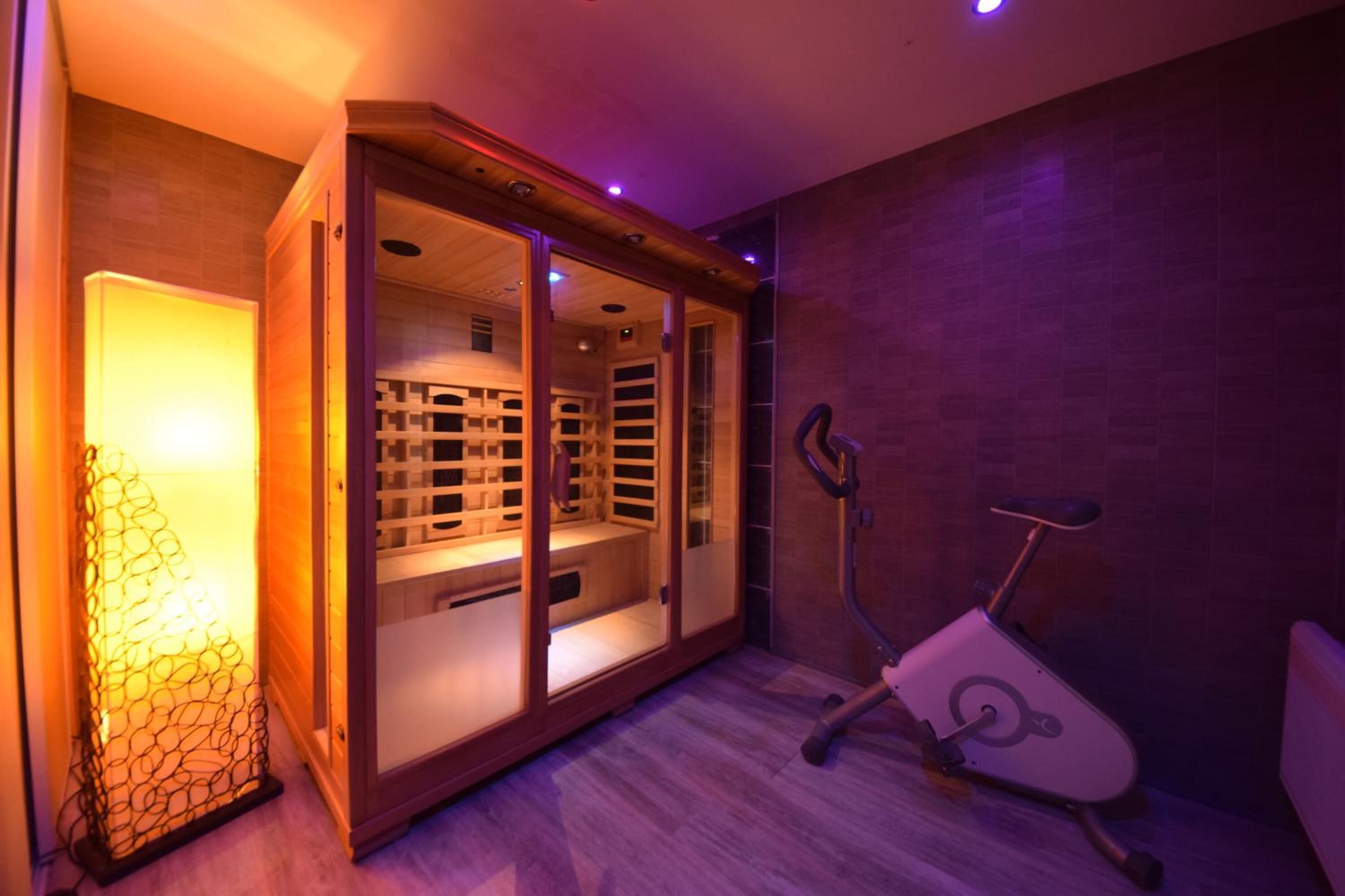 Habitación con sauna, bicicleta estática y un armario de madera con estantes.
